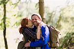 Portrait smiling couple kissing hiking in woods