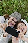 Overhead view smiling women taking selfie with camera phone in grass