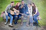 Friends with guitar taking selfie with camera phone at campsite