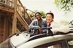 Portrait smiling couple standing in car sunroof outside cabin