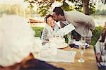 Boyfriend kissing girlfriend with birthday gift at lakeside patio table