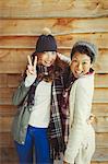 Portrait smiling female friends gesturing peace sign outside cabin