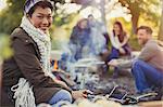 Portrait smiling woman drinking beer with friends at campfire