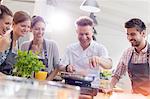 Students watching teacher in cooking class kitchen