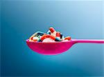 Medicine capsules in pink spoon against blue background