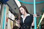 Businesswoman using cellphone in Docklands Light Railway train, London