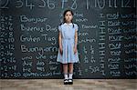 Portrait of schoolgirl standing in front of large chalkboard with schoolwork chalked on it