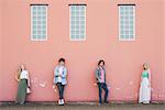 Friends standing against pink wall background