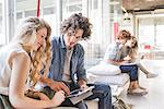 Co-workers working on laptop on sofa by window