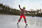 Boy balancing whilst ice skating on frozen lake, Gavle, Sweden