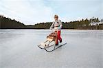 Boy pushing logs on kicksled across frozen lake, Gavle, Sweden