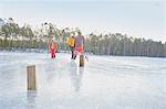 Senior man and boys practicing ice skating slalom on frozen lake, Gavle, Sweden