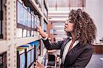 Young businesswoman searching office shelves