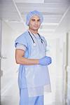 Portrait of male doctor wearing scrubs in hospital corridor