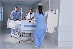 Doctor and medical running with patient bed in hospital emergency