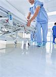 Two medics urgently pushing hospital bed along corridor