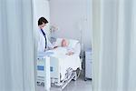 Female doctor talking to senior female patient in hospital bed