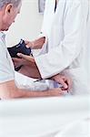 Cropped shot of female doctor using blood pressure gauge on senior male patient on hospital bed