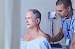 Male nurse listening to senior male patient back with stethoscope