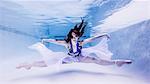 Underwater view of teenage girl, wearing ballet shoes, in dance position