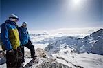 Two male snowboarders looking out over snow-covered landscape, Trient, Swiss Alps, Switzerland