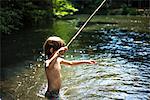 Boy waist deep in water holding stick