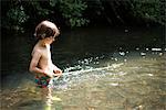 Boy waist deep in water holding stick