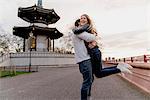 Happy young man hugging girlfriend in Battersea Park, London, UK