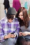 Two teenagers sitting on bench with mobile phone