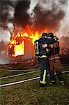 Fire fighters embracing in front of burning buildings