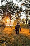 Hunter walking through field at sunset