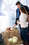 Man and woman looking at produce on hay bale in greenhouse