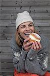 Portrait of woman wearing warm clothing eating cake