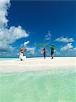 Boys playing on sandy beach while mother taking photo