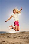 Happy young woman jumping on beach