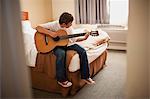 Boy practicing guitar in his bedroom
