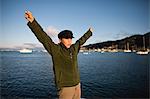 Boy with arms outstretched beside sea