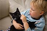 A young boy cuddles his cat.