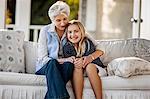 Happy mature woman sitting with her young granddaughter on their porch.