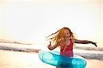 Young girl playing with an inflatable ring at the beach.