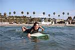 Young woman heading into the surf on a surfboard.