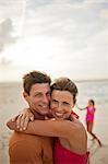 Portrait of a smiling mid-adult couple hugging on a sandy beach.