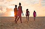 Mid-adult couple and their two teenage daughters walking together along a beach.