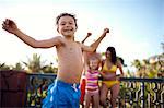 Portrait of a smiling young boy about to jump into a swimming pool.