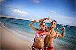 Happy young couple flexing their muscles on a beach.