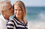 Mid adult woman being affectionate with her husband on the beach.