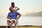 Mature man receiving shoulder massage from his wife by the beach.