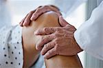 Doctor's hands examining a patient's knee.