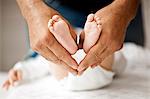 Close up of man's hands holding his baby's feet and creating heart shape.