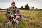 Hunter holding pigeon and rifle, smiling, portrait